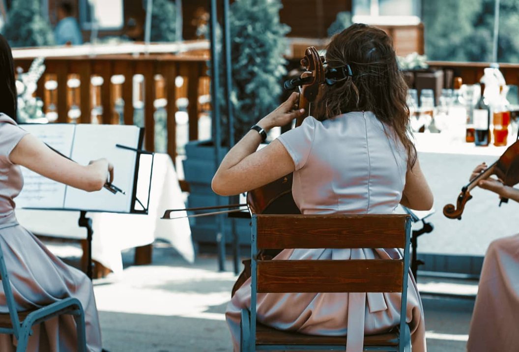 String quartet performing outdoors seen from behind, wearing white