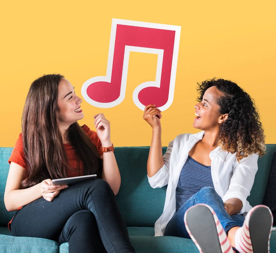 Two women on couch holding large music note icon