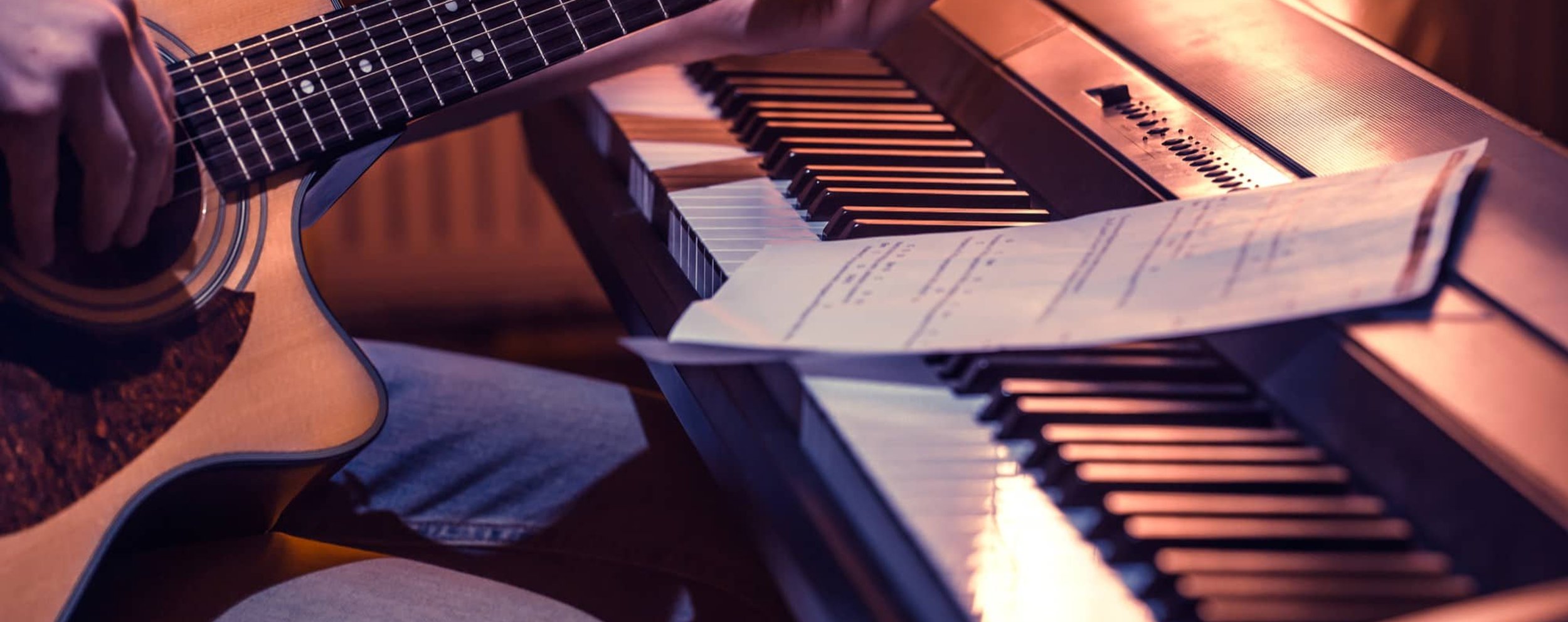 Guitar and keyboard with sheet music in warm lighting