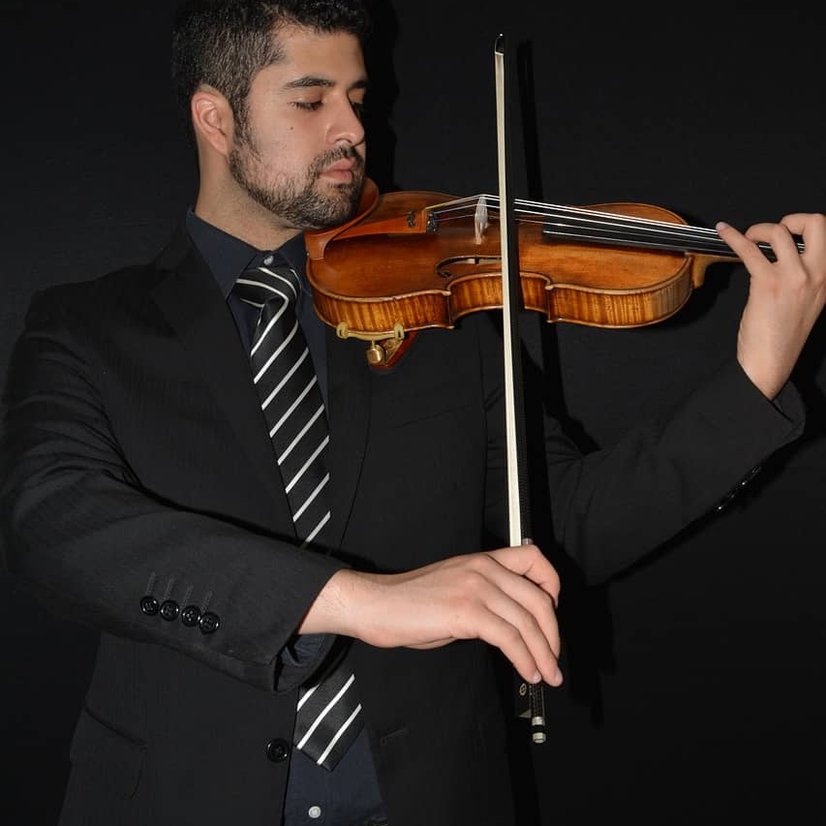 Man in suit playing violin against black background