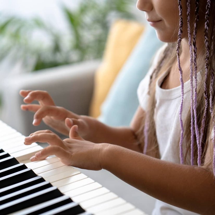 Girl with braids playing piano keys at home