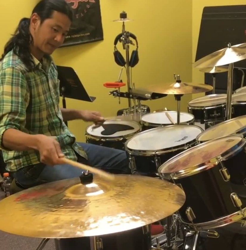 Man playing drum set in yellow practice room indoors